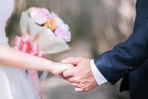 liefdevolle jonge liefde getrouwd stel hand in hand en staan samen in ceremonie trouwdag trouwen scene. jong liefdespaar wees hand in hand pinky belofte of pink zweer. foto