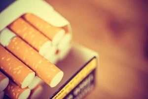 afbeelding van verschillende commercieel gemaakte sigaretten. stapel sigaret op houten. of niet-roken campagneconcept, tabak. vintage retro filteren. foto