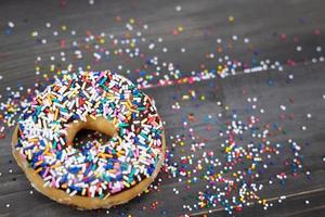 donuts met chocolade glazuur, topping hagelslag donut kleurrijke variëteit en verscheidenheid aan smaken mix van multi gekleurde zoete donuts met frosted bestrooid op een houten achtergrond. bovenaanzicht foto