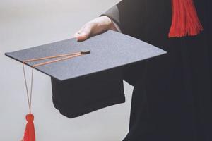 afgestudeerden, close-up student met hoeden en kwastje rood in de hand tijdens aanvangssucces van de universiteit, felicitatie van conceptonderwijs. diploma uitreiking. foto