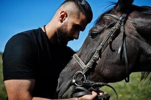 Arabische lange baard man slijtage in het zwart met Arabisch paard. foto