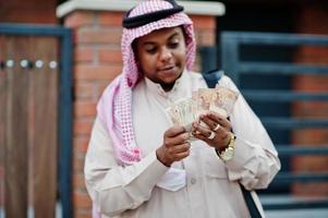 Midden-Oosten Arabische zakenman poseerde op straat tegen modern gebouw met zwarte handtas en eurogeld. foto