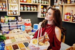 meisje in het rood met verschillende producten op de mand bij deli store. foto