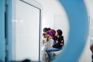 Afro-Amerikaanse vrouw die make-up toepast door visagist bij beauty salon. foto