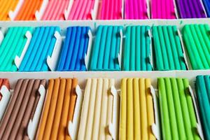 regenboogkleuren van boetseerklei. veelkleurige plasticinestaven in een doos, achtergrondtextuur foto