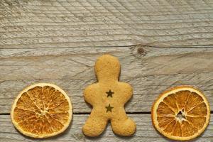 bovenaanzicht van gedroogde sinaasappelschijfjes en gemberbrood man op houten achtergrond. feestelijke kerstwenskaart met kopieerruimte voor uw projecten foto