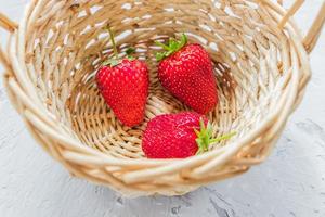 verse biologische aardbeien in een mand op grijze gestructureerde achtergrond. foto