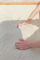 close-up van de handen van het kind die in de zandbak spelen foto