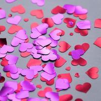 donkere achtergrond met rode en paarse harten confetti voor Valentijnsdag. selectieve aandacht. feestelijk en vakantieconcept. foto