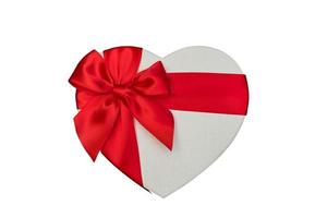hartvormige geschenkdoos en rood satijnen lint geïsoleerd op een witte achtergrond. foto