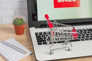 kleine rode winkelwagen of trolley op laptop toetsenbord, technologie business online shopping concept foto