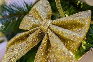 Kerstmis en Nieuwjaar vakantie achtergrond. kerstboom versierd met gouden sprankelende strik. viering concept foto