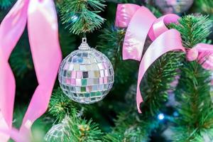 Kerstmis en Nieuwjaar vakantie achtergrond. kerstboom versierd met zilveren diskoballen, strikken en slingers. glinsterend en sprankelend. viering concept foto