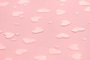 roze achtergrond met roze harten confetti voor Valentijnsdag. selectieve aandacht. feestelijk en vakantieconcept. foto