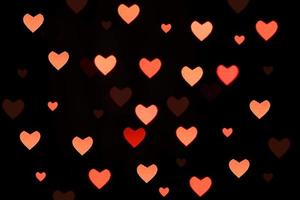 roze harten bokeh op zwarte achtergrond. feestelijke textuur voor vakantie foto