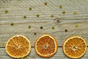 vintage houten achtergrond met kerstkrans - gedroogde stukjes sinaasappel en gouden confetti in de vorm van een ster. bovenaanzicht met kopieerruimte foto