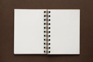 bovenaanzicht van open lege notebook met omslag van gerecycled papier op bruine kleurrijke achtergrond foto