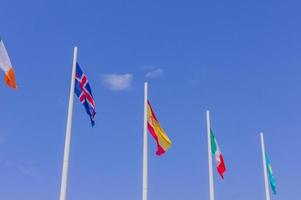 kleurrijke vlaggen van verschillende landen die op blauwe hemelachtergrond golven foto