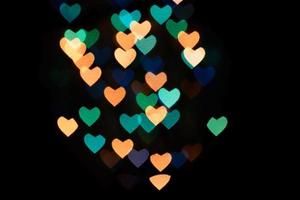 veelkleurige harten bokeh van blauwe en oranje colores op zwarte achtergrond. textuur voor foto