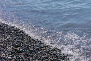 kiezelstrand. kust met transparant water en kleine steentjes foto