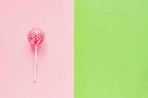 zoete smakelijke roze lolly op groene en roze achtergrond. minimale flatlay met kopieerruimte foto