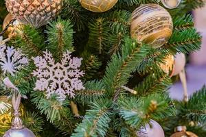 close-up van de kerstboom versierd met gouden en witte ballen en sneeuwvlok. nieuwjaar achtergrond foto