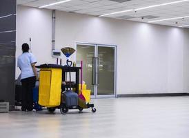 schoonmaakapparatuur voor auto's met waarschuwingsborden aan het schoonmaken de vloer in het gebouw en de meid is aan het werk foto