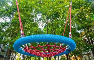 rond schommelzitje van gaas in speelplaats. leeg blauw touw web nest voor swingende close-up. foto