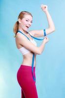 fitness meisje sportieve vrouw haar biceps op blauw meten foto