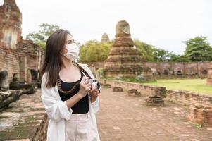 jong mooi vrouw vervelend beschermend masker op reis en nemen foto Bij Thais historisch park, vakantie en cultureel toerisme concept.