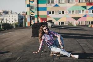 leerling vrouw in zonnebril en zittend Aan skateboard foto