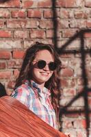 meisje in zonnebril met een longboard foto