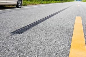 een detailopname lage hoek visie, een lang lijn van zwart banden stoppen met geweld tegen de geplaveid weg oppervlak. foto