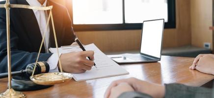 zakenvrouw en advocaten bespreken contractpapieren met koperen schaal op houten bureau in kantoor. wet, juridische diensten, advies, rechtvaardigheidsconcept. foto