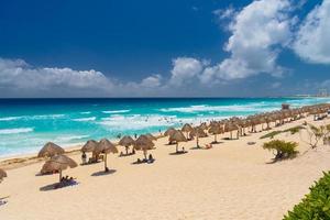 paraplu's op een zandstrand met azuurblauw water op een zonnige dag in de buurt van cancun, mexico foto