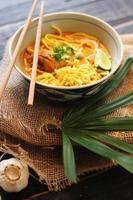 khao dus ik recept, khao soi, khao dus ik kai, Thais noedels khao dus ik, kip kerrie met kruiderij geserveerd Aan zwart houten tafel met decoratief bladeren, verticaal foto. foto