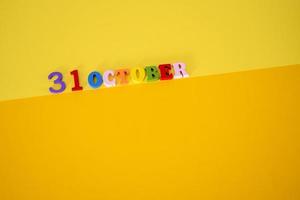 oktober 31 Aan een geel, papier achtergrond met houten en veelkleurig brieven met ruimte voor tekst. foto