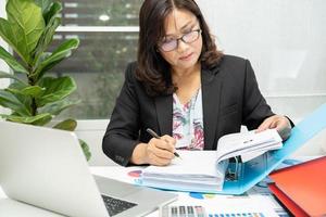 Aziatische accountant werkt en analyseert financiële rapporten projectboekhouding met grafiekgrafiek en rekenmachine in modern kantoor, financiën en bedrijfsconcept. foto