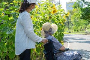 verzorger hulp en zorg Aziatische senior of oudere oude dame vrouw patiënt zittend en gelukkig op rolstoel in park, gezond sterk medisch concept. foto