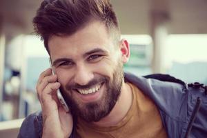 knap jong gewoontjes bedrijf Mens met baard gebruik makend van cel telefoon foto