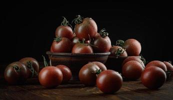 een veel van rijp sappig tomaten Aan een zwart achtergrond. zwart tomaten. foto