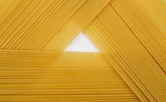 dun pasta geregeld in rijen. geel Italiaans pasta. lang spaghetti. rauw spaghetti behang. dun spaghetti. voedsel achtergrond concept. foto
