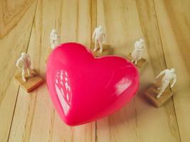roze hart en witte figuur op houten tafel voor gezondheid, medische inhoud. foto