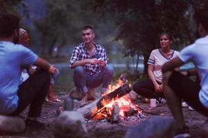 jong vrienden ontspannende in de omgeving van kampvuur foto