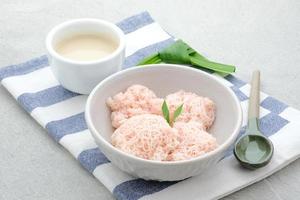 kue putu mayang is traditioneel Indonesisch tussendoortje gemaakt van rijst- meel strengen gekruld omhoog in een bal, geserveerd met kokosnoot melk en palm suiker. foto