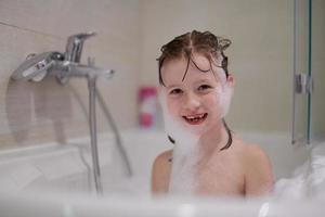 weinig meisje in bad spelen met zeep schuim foto