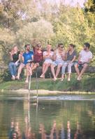 vrienden genieten van watermeloen terwijl zittend Aan de houten brug foto