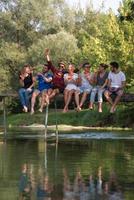 vrienden genieten van watermeloen terwijl zittend Aan de houten brug foto