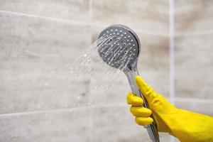 vrouwelijke hand houdt douchekop vast met stromend water, kopieer ruimte foto