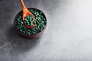 biologisch spirulina tablets in een houten kop met een houten lepel foto